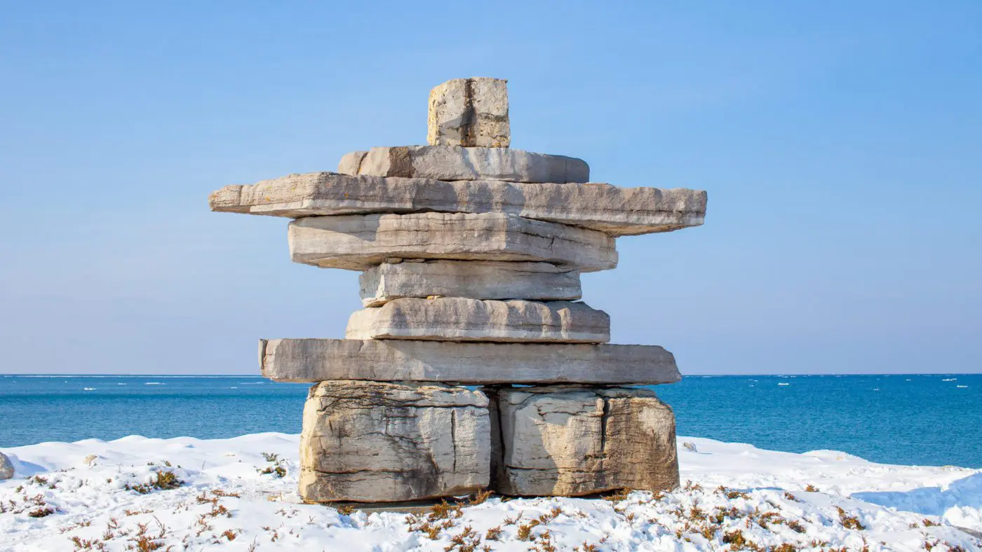 a stone inukshuk on the beach in the winter | things to do in collingwood ontario