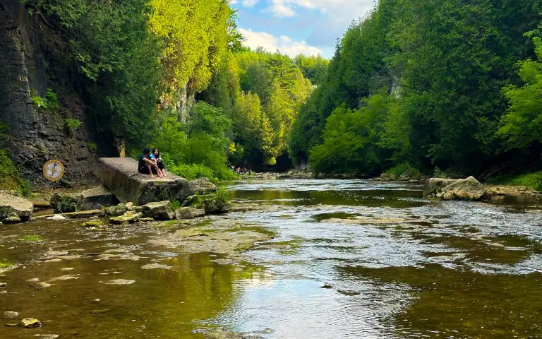 elora gorge conservation area - a couple of people sitting on a rock ledge by a river