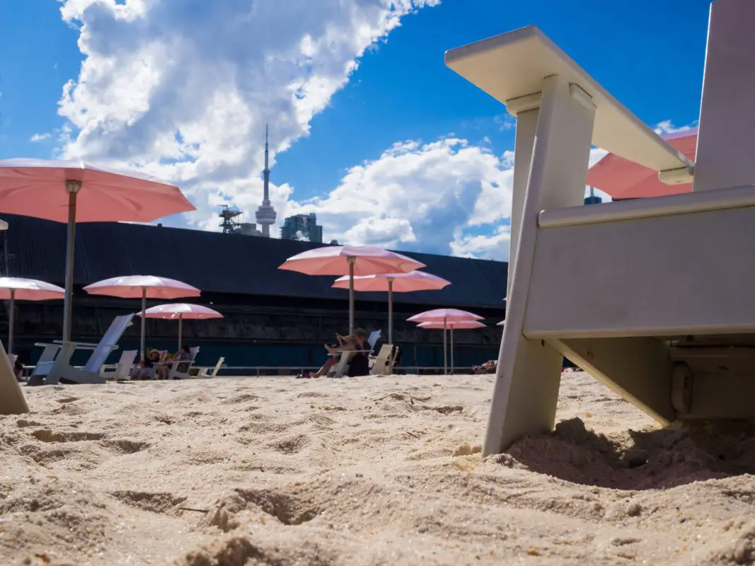 several sun umbrellas and Adirondack chairs on the beach | best beaches in ontario
