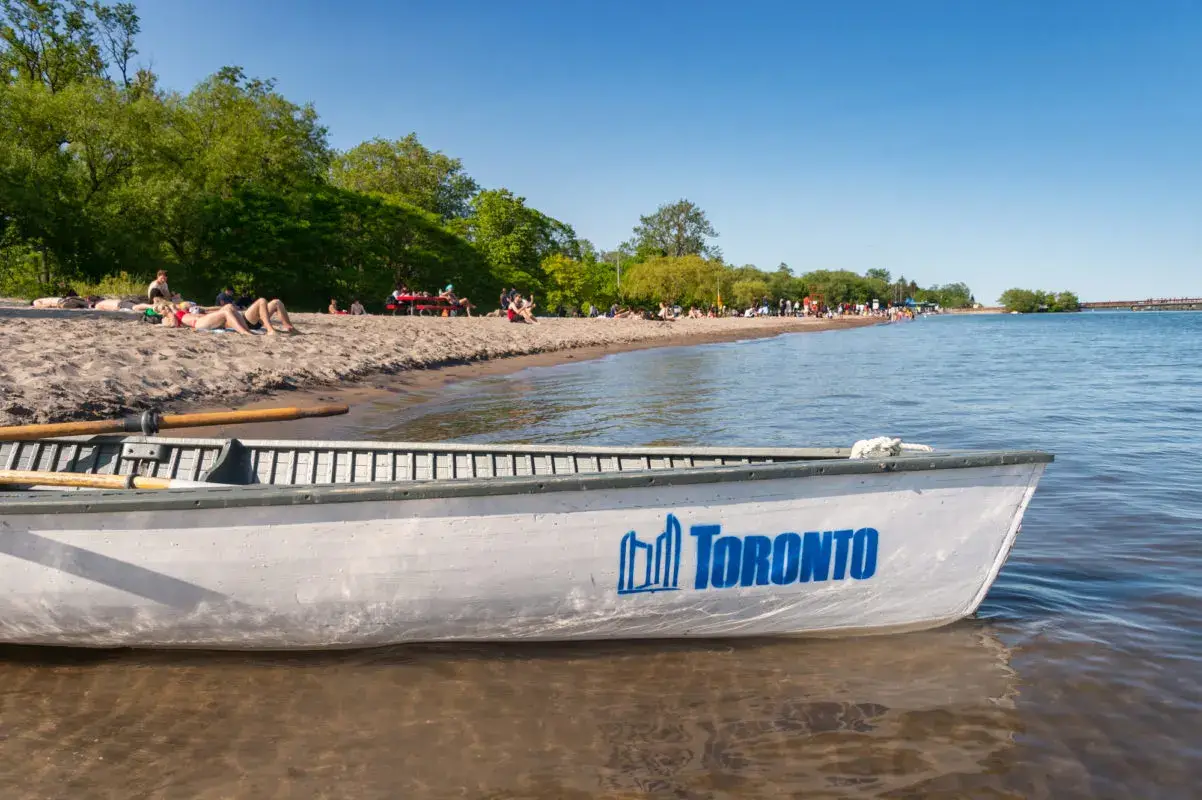 canoe in the water on a beach full of people | beautiful beaches in ontario