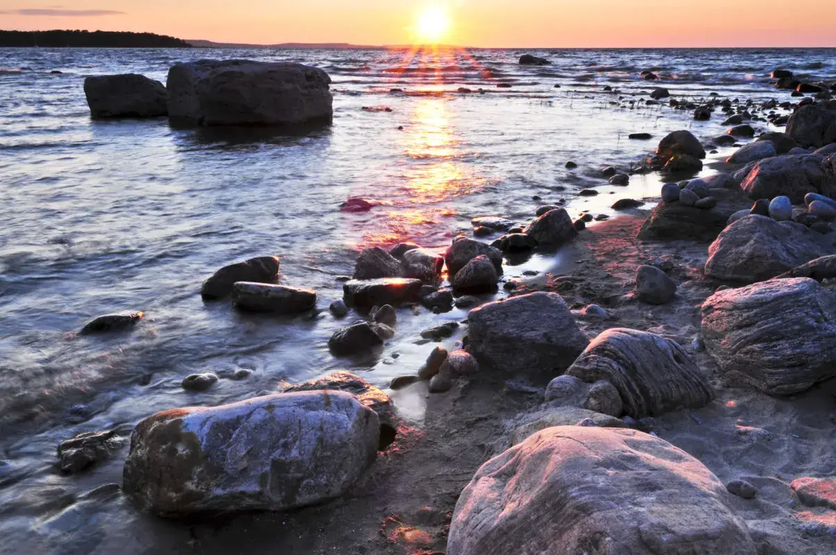 large rocks in the sand on the shore of a lake | beaches in ontario