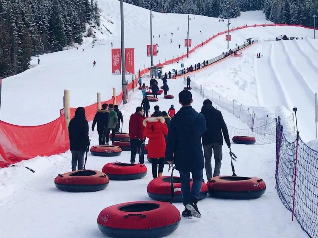 several people in line at a snow tubing hill | things to do in winter