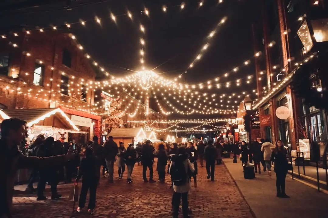 People walking down a busy pedestrian road with Christmas lights and shops on both sides | winter activities in Ontario