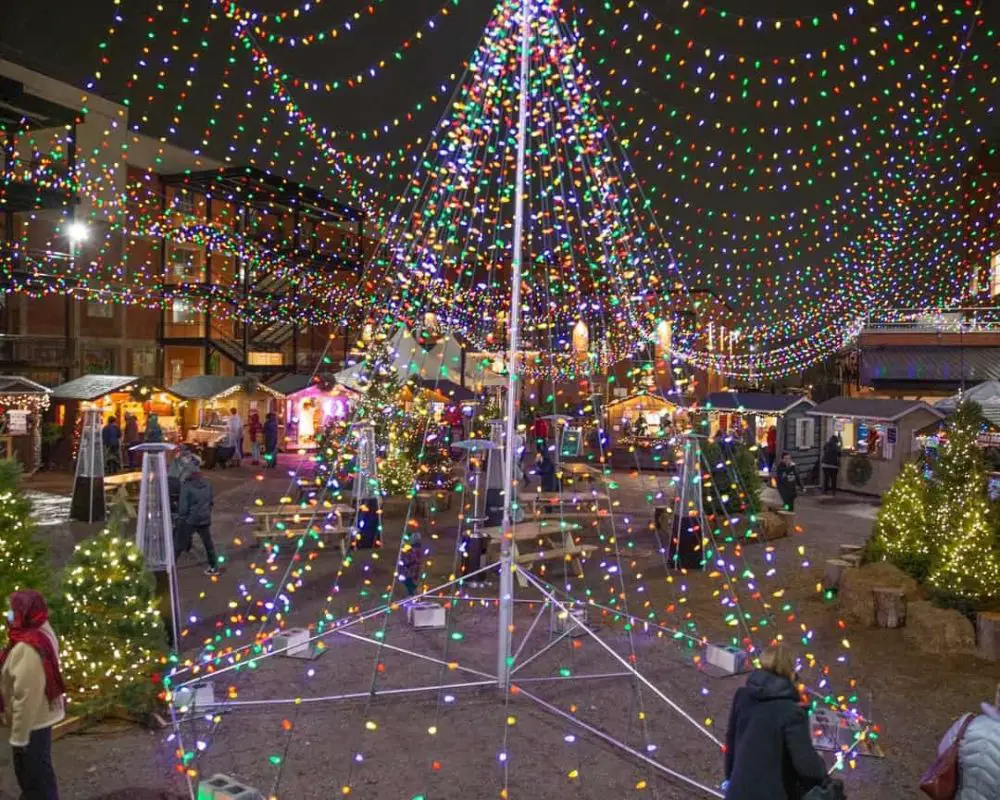 Christmas tree made out of strings of lights in an outdoor market space | christmas markets