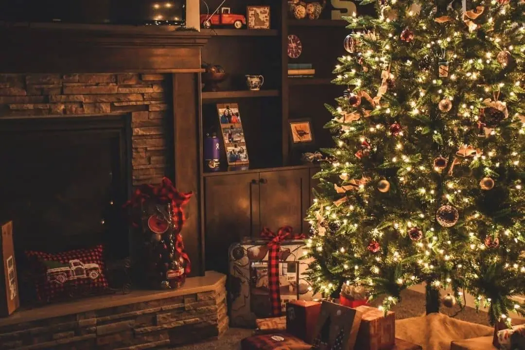 christmas tree illuminated at night in a living room, surrounded by presents | christmas getaways