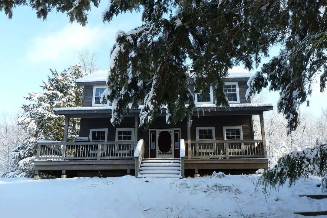 Grey house covered in snow and surounded by trees | christmas getaways ontario