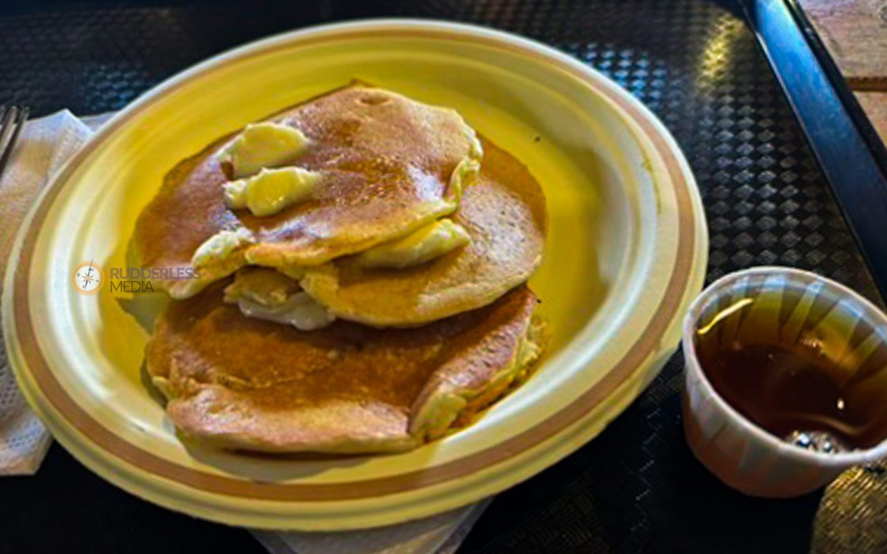 pancakes on a disposable plate next to a cup of maple syrup | maple syrup festivals ontario