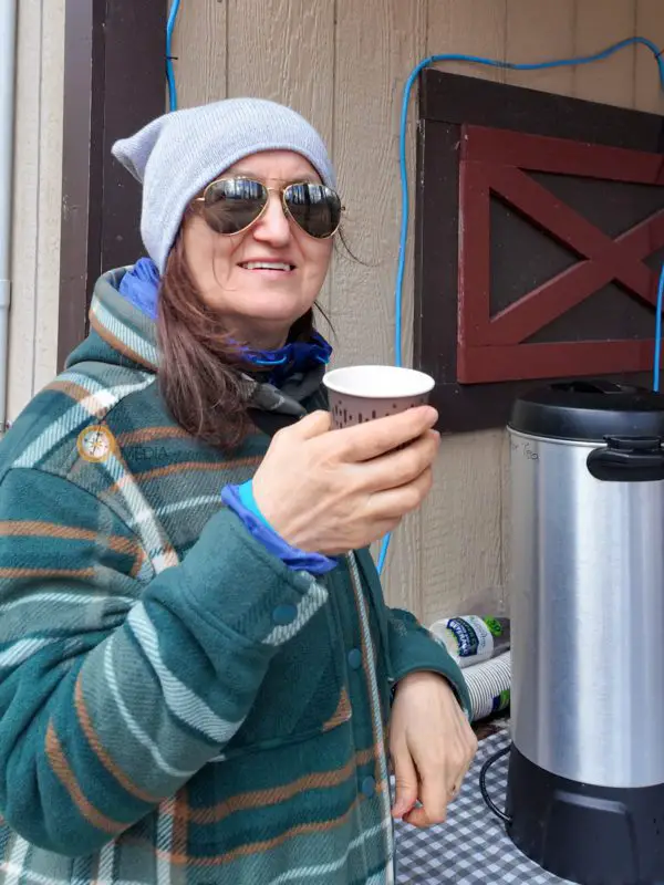 a woman in warm clothing holding a cup of coffee outside | maple syrup festivals ontario